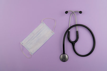 Medical mask and stethoscope on a purple background. Top view.の写真素材