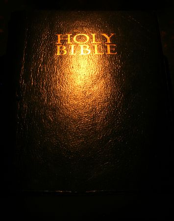 A bible open on a table next to a candleの写真素材