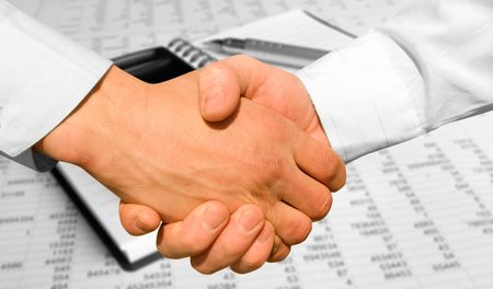 handshake over paper and pen,blurry computer in the backgroundの写真素材
