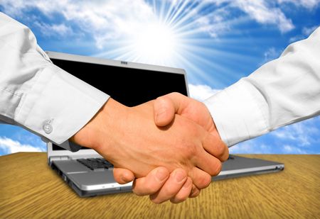 handshake over paper and pen,blurry computer in the backgroundの写真素材