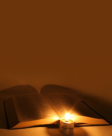 A bible open on a table next to a candleの写真素材