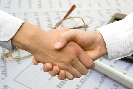 handshake over paper and pen,blurry computer in the backgroundの写真素材