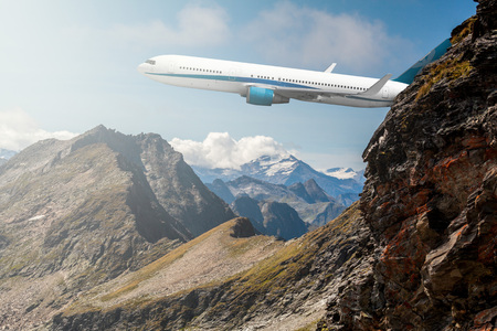 airplane flies over the mountains with a view of the sun backgroundの写真素材