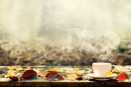 hot coffee on the table on a autumn backgroundの写真素材