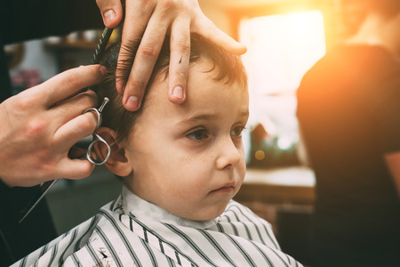 The child is being cut hairstyles in the hairdressing salonの写真素材
