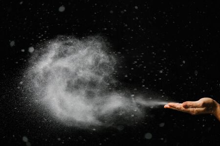 snow blows from hands on black backgroundの写真素材