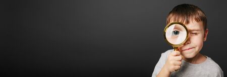 Child see through magnifying glass on the black backgrounds. Big kid eyeの写真素材