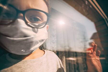 a child in quarantine because of a virus sits at home in a mask and looks out the window on a sunny day.
Coronavirus and Air pollution pm2.5 concept. COVID-19の写真素材