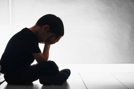child with depression is sitting on the floorの写真素材