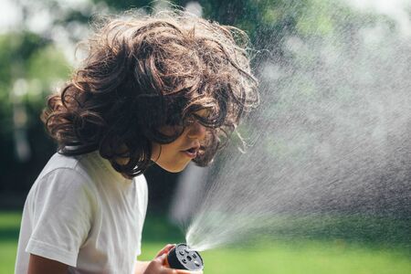 child plays with water in the backyard in the gardenの写真素材