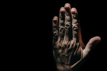 man's praying hands in the dark