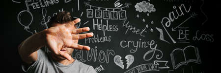 a man in depression close with his hand on the background of a drawn blackboard with problems