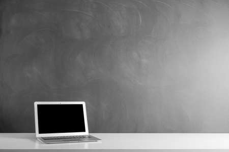 modern laptop computer on the tabl on the blackboard backgroundの写真素材