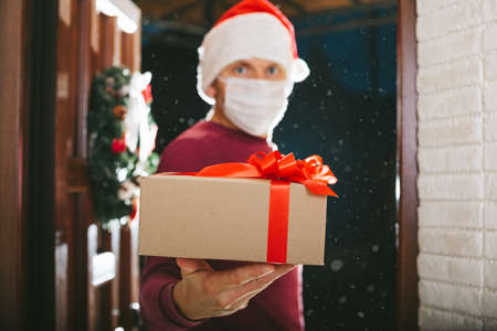 courier delivers a gift on Christmas Eve in a mask from the coronavirusの写真素材