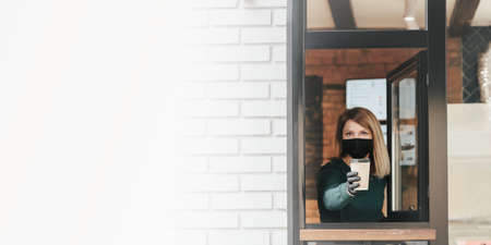 Masked barista spills coffee through the window because of coronavirus