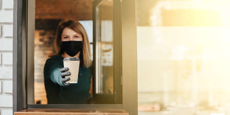 Masked barista spills coffee through the window because of coronavirusの写真素材