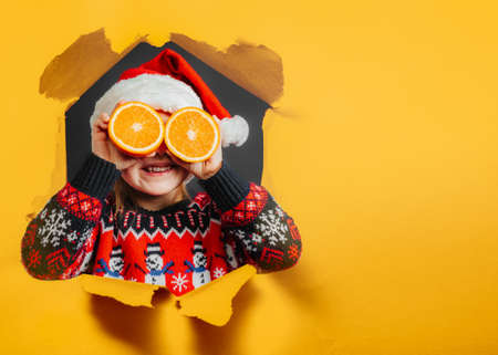 child looking at christmas present through orange on black backgroundの写真素材