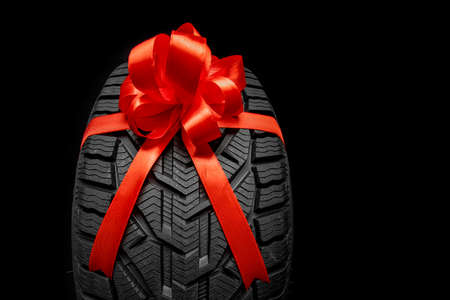black isolation rubber tire, on the gray backgrounds in a bow for christmasの写真素材