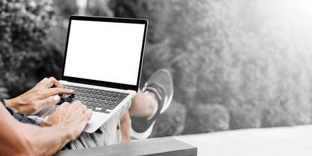 a man works in nature, sitting in a chair with a laptop
