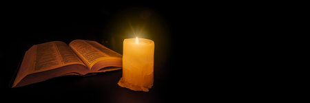 bible on the table in the light of a candleの写真素材
