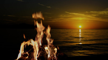 a bonfire burns at night against the background of mountains and sea with bright starsの写真素材