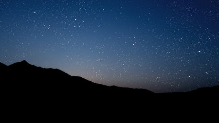 a movement of stars in the night sky with the view of mountains. . High quality photoの写真素材