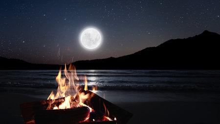 bonfire burns at night against the background of mountains and sea with bright stars...の写真素材