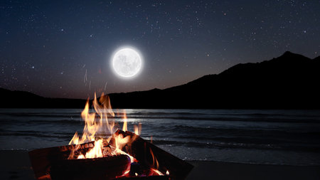 bonfire burns at night against the background of mountains and sea with bright stars...の写真素材