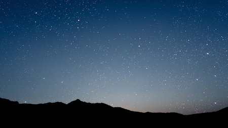 a movement of stars in the night sky with the view of mountains. . High quality photoの写真素材