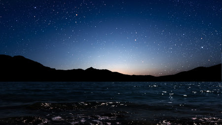 a movement of stars in the night sky with the view of mountains.の写真素材