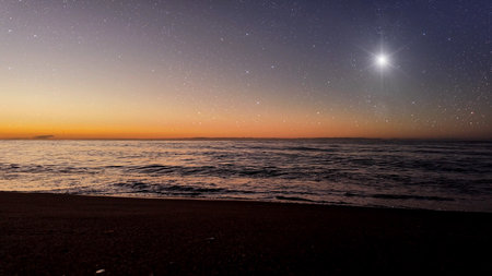 a movement of stars in the night sky with the view of the ocean. High quality photoの写真素材