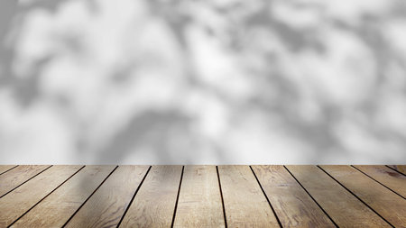 The shadow of the trees gently swaying in the breeze, on a white background with a wooden table.