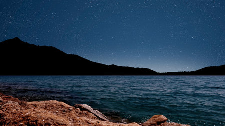 Sunrise over the sea with gentle waves and fading stars in a peaceful, dreamy atmosphereの写真素材