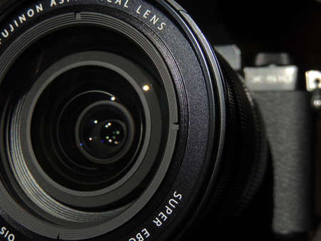 Fujifilm X-S10 with 16-80mm lens black. New for the end of 2020. The best camera for videographers. Great option in 2021.on a dark light background. Open lens (objective). Macro.のeditorial素材