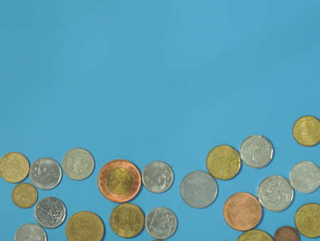 Iron coins of many countries and different currencies on a blue background. Macro. The ruble. Euro....