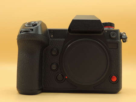 A black medium-format camera with a CMOS sensor. Yellow background. Macro photography.
