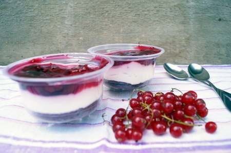 Delicious parfait dessert with bilberry berries, milk souffle and jello layers. Frozen treat in a glass on a rustic wooden backgroundの写真素材