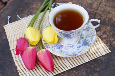 Tea cup, tulip flower, on wooden background. Spring composition.の写真素材