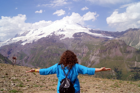 Young woman with arms outstretched in the mountains. The concept of happiness, freedom, pleasure.