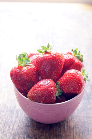 Fresh strawberries in a bowl on a wooden table. Fresh strawberries in a bowl on a wooden table. Vegetarianism, vegan. The concept of health, proper nutrition, diet.の写真素材