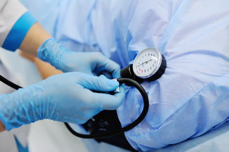 Doctor measures the patient tonometer pressure against the background of a surgical operating room....