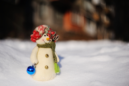 funny snowman in a hat with Christmas toys on a background of snow driftsの写真素材