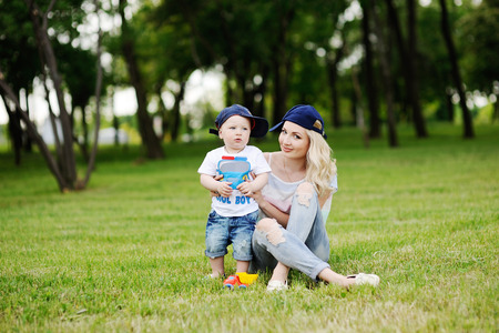 Mother and young son in caps playing in the park on the grass