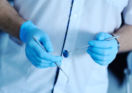 dental instruments in the hands of the doctor. Dentist in sterile latex gloves holding dental tools Close-upの写真素材