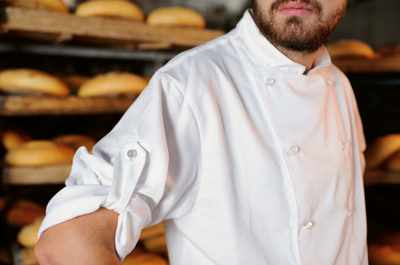 young guy with a beard in a white apron on the background bakeryの写真素材