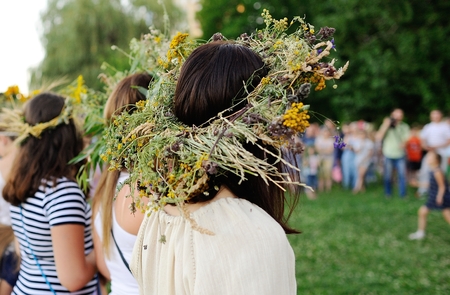 Girls with wreaths of wild flowers lead round dance on the background of people. Feast of Ivan Kupala. Midsummer day. Easterの写真素材