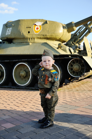 Baby boy in military uniform on tank background. May 9, World War II, defender, February 23.の写真素材
