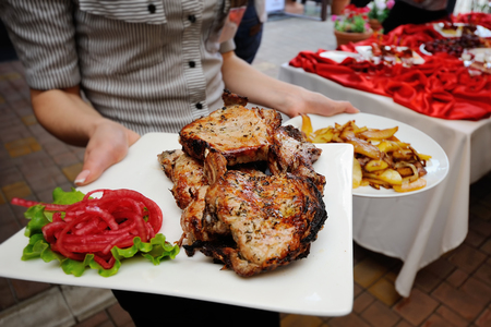 The waiter brings fried steak and potatoes. Caucasian kitchenの写真素材