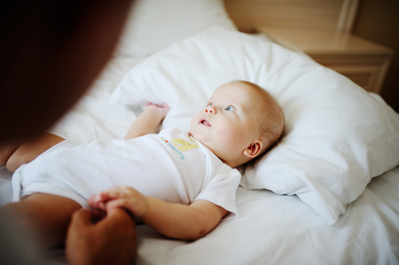 Dad playing with baby boy on white bedの写真素材
