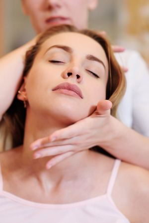 the massage therapist does a neck massage to a pretty pregnant girlの写真素材